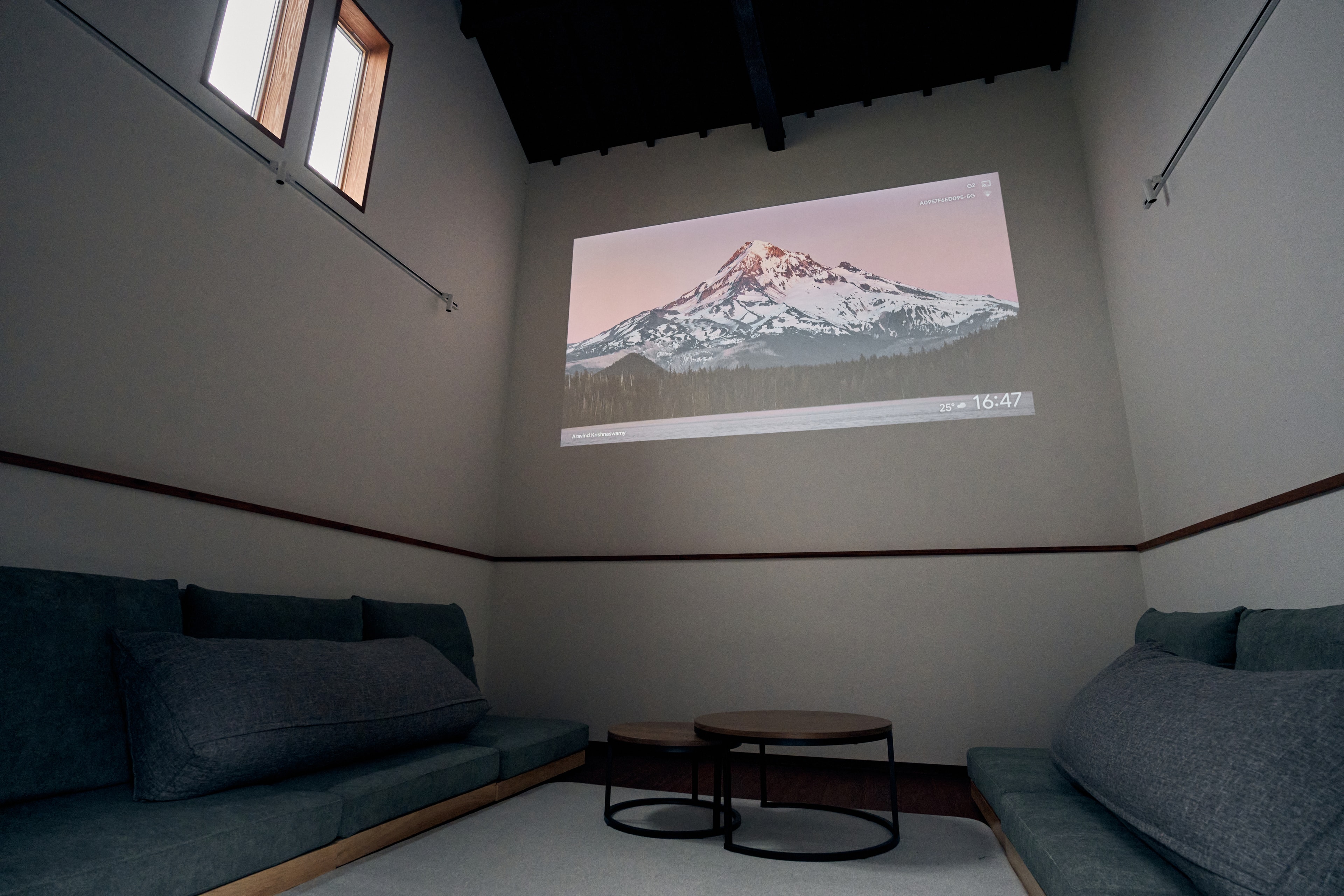 The annex theater room with low sofas and a wall-projected mountain scene
