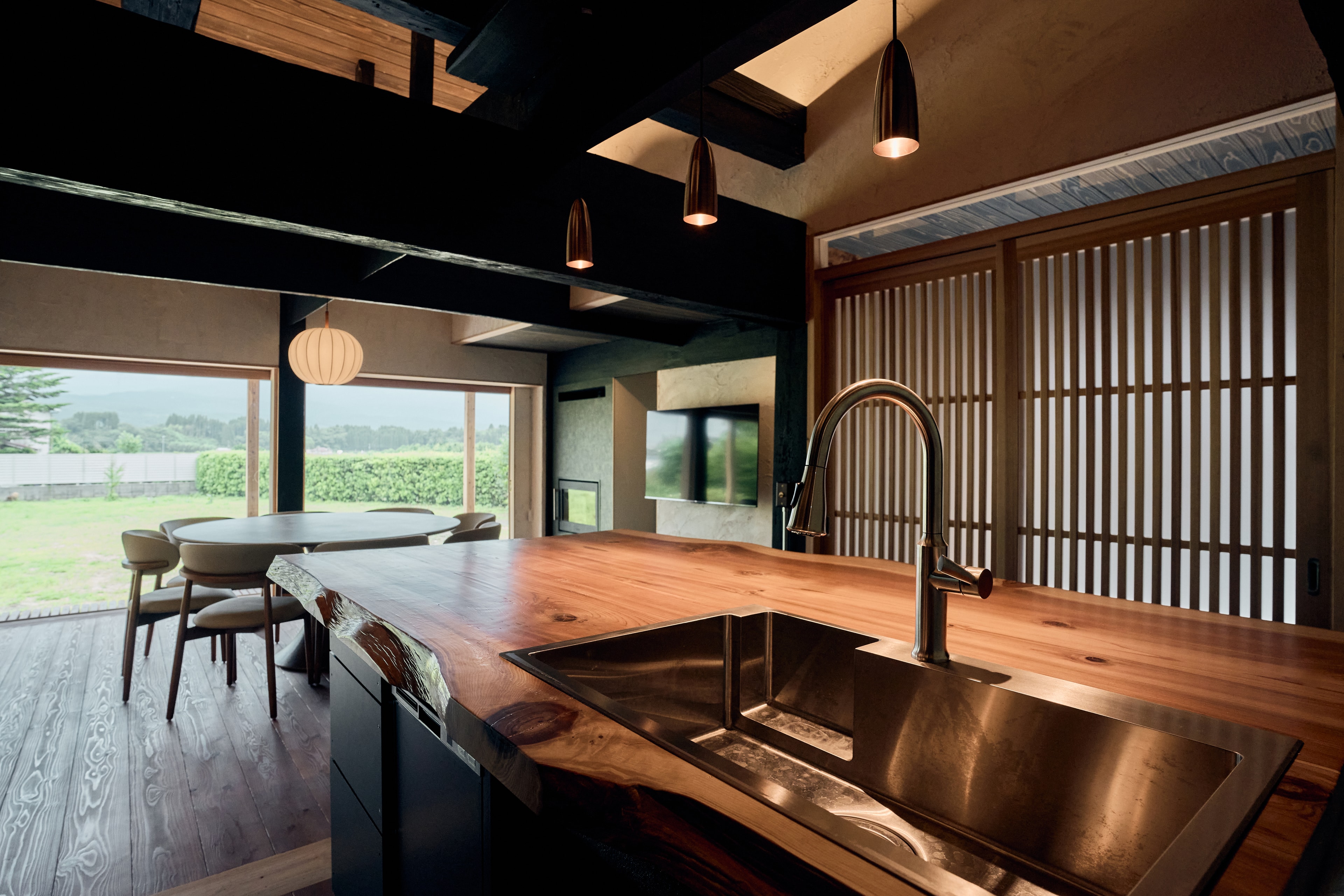 The main house kitchen island in live-edge cedar, with the dining table and garden view